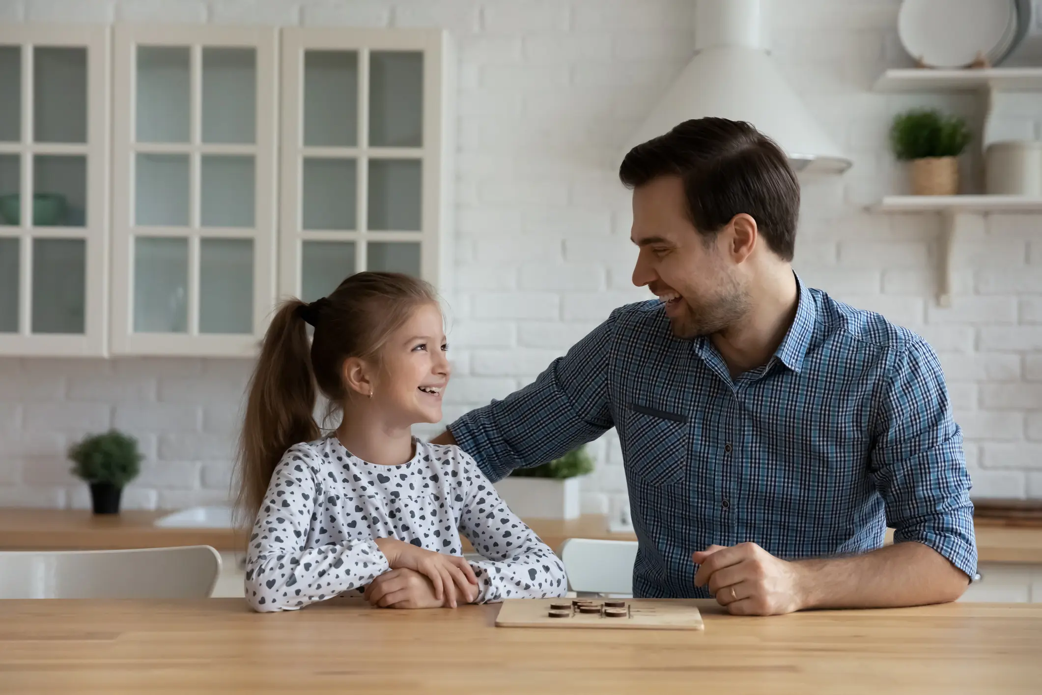 Joyful excited daddy and daughter kid playing checker draughts in kitchen, having fun, laughing. Happy father and girl enjoying board game and leisure, improving brain tactical and logical skills