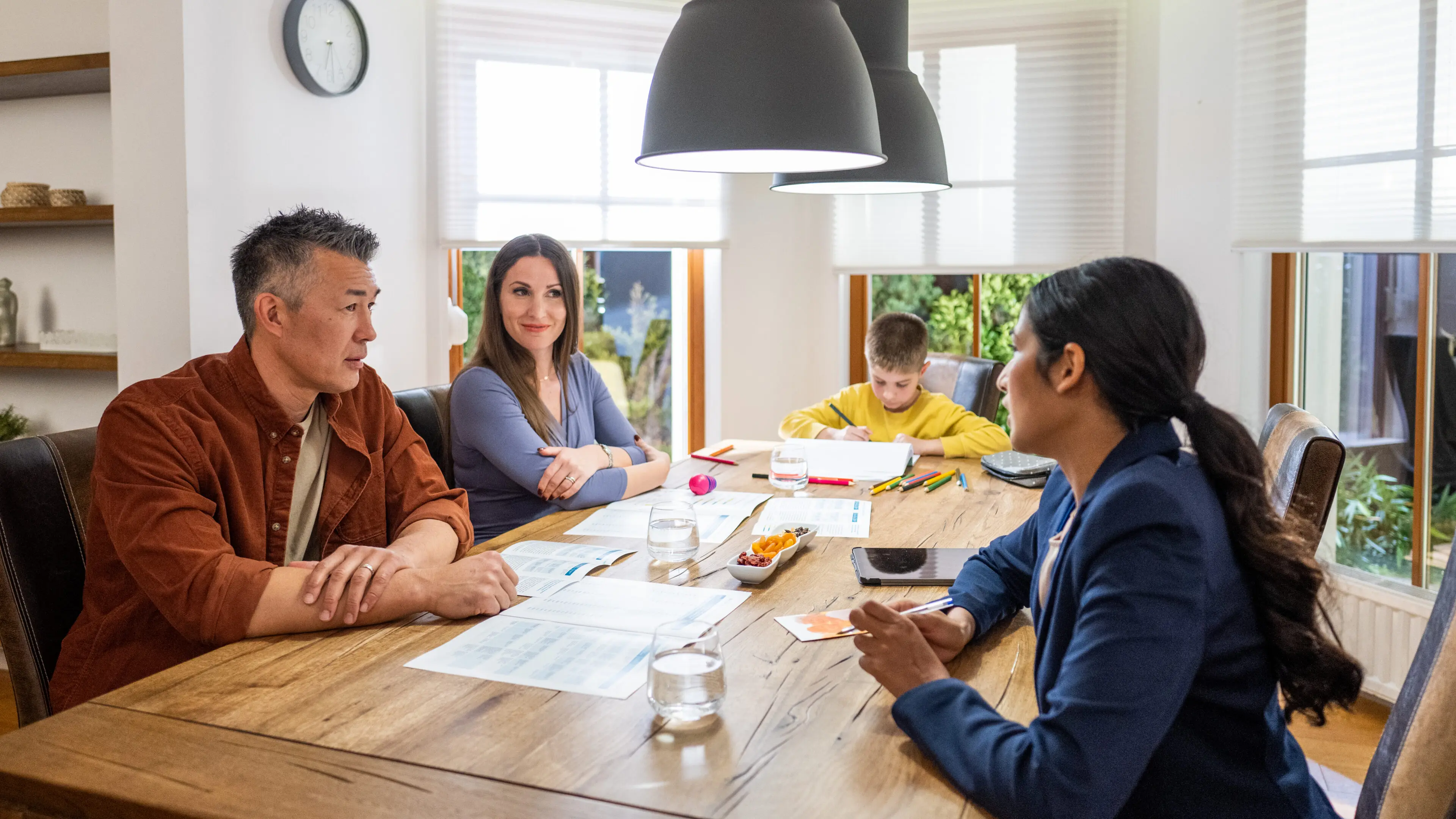 Mature couple discussion with financial advisor while sitting at table in house.