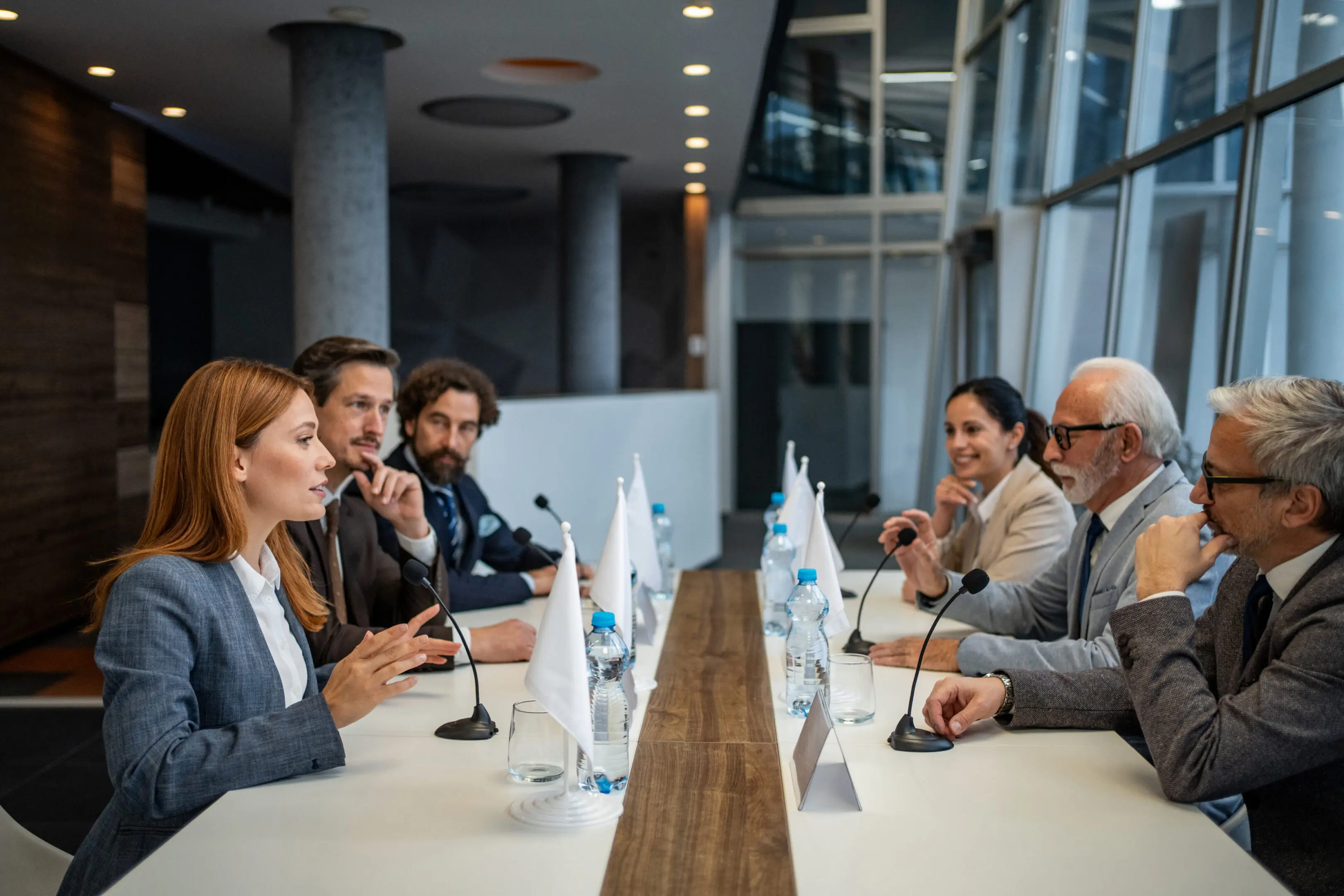 Group of diverse politicians and delegates discussing global policy during an important international summit, engaging in diplomacy and serious negotiations around a conference table